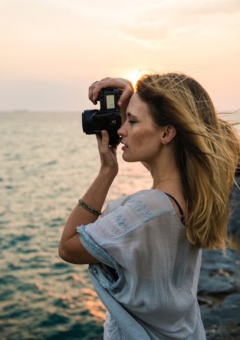 woman taking photo near body of water during daytime