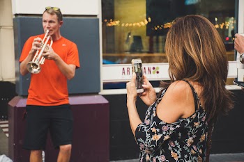 Woman Taking Photo of Man Playing Trumpet