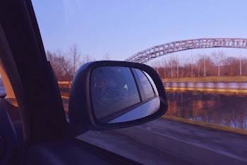Woman Taking Self Portrait from Moving Car's Side Mirror