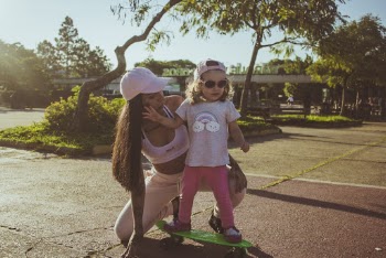 Woman Teaching Toddler To Ride Penny Board