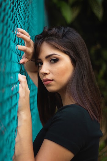 Woman Touching Blue Metal Wire Fence Wearing Black Shirt