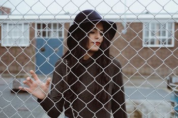 woman touching cyclone fence