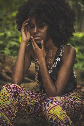 Woman Touching Face While Sitting on Tree Branch