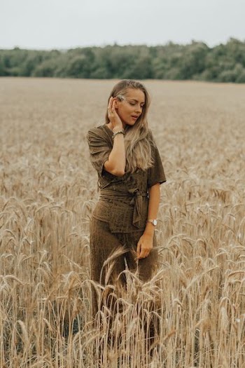 woman touching her ear with her right hand standing in wheat field