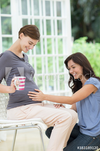 Woman touching stomach of pregnant friend