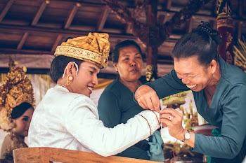 Woman Tying String on Man's Sleeve