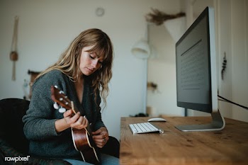 Woman using a computer while playing ukulele during quarantine  | Free  photo - 2328030