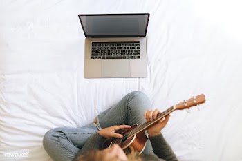 Woman using a laptop while playing ukulele during lockdown | Free  photo - 2329924