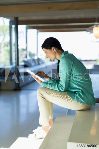 Woman using digital tablet on sunny staircase
