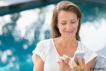 Woman using smart phone at poolside