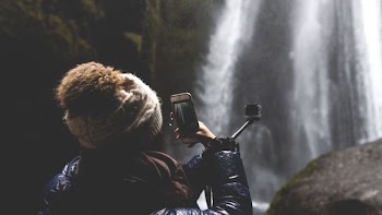 woman using smartphone and holding black selfie stick