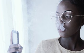 woman using smartphone beside curtains