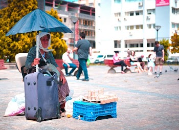Woman Using Umbrella Near Luggage and Crate