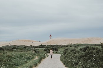woman walking beside green grasses during daytime