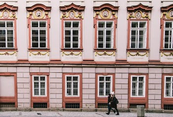 woman walking beside pink building