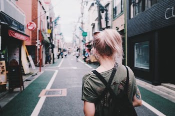 woman walking between brown and black buildings during daytime