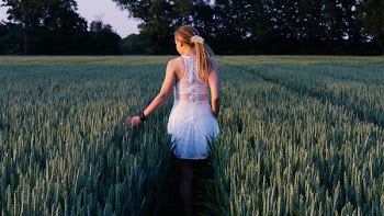Woman Walking in Between Grass Field at Daytime