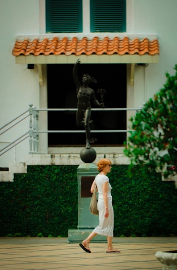 Woman Walking in Front Of Statue