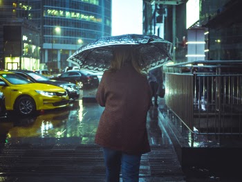 Woman Walking in Street With Umbrella during Nighttime