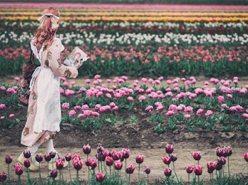 woman walking near field of tulip flower at day time