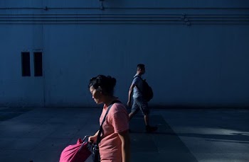woman walking near man beside white wall at daytime