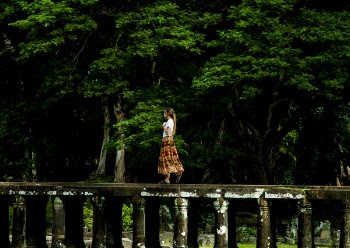 Woman Walking on Bridge Surrounded by Trees