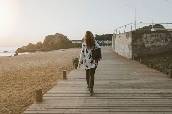 woman walking on brown boardwalk under cloudy skies outdoors