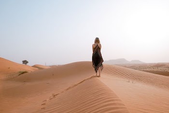woman walking on desert during daytime
