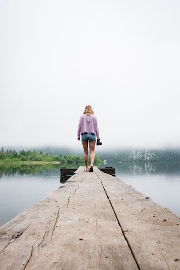 woman walking on dockside beside body of water