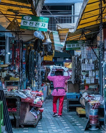 Woman Walking on Pathway Between Stores