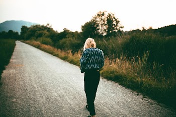 Woman Walking on Road Near Grasses