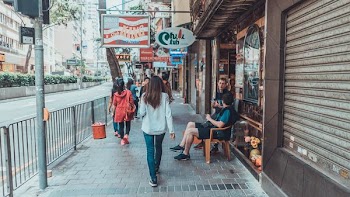 woman walking on sidewalk near rail and stores