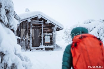 Woman walking to a hut in the snowy woods