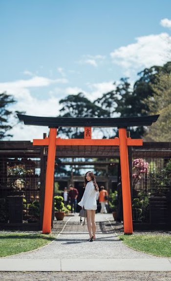 woman walking towards red and black pagoda arch