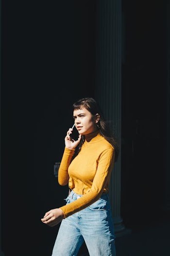 woman walking with phone on her right ear during daytime