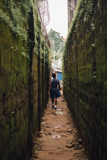 Woman Walks at the Alley Between Concrete Walls