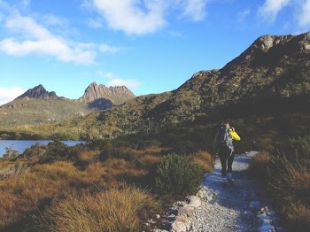 woman walks on dirty road leading to mountain