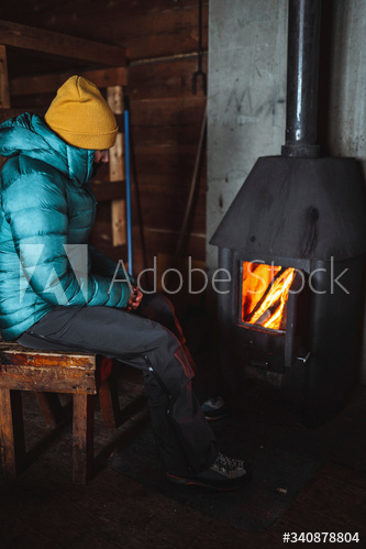 Woman warming up near a fireplace in a hut