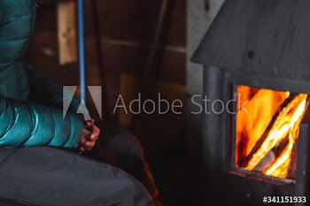 Woman warming up near a fireplace in a hut