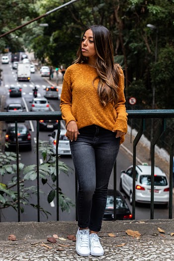 Woman wearing a brown shirt leaning on black metal rails