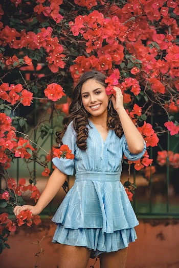 Woman wearing a dress standing near red flowers  