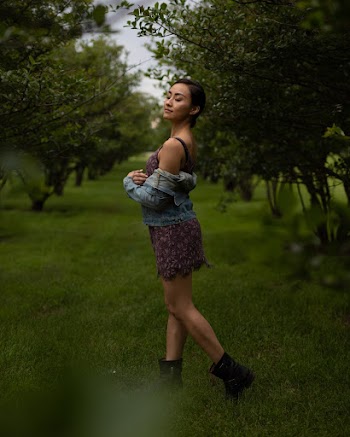 Woman wearing a floral dress and a denim jacket posing for a photo