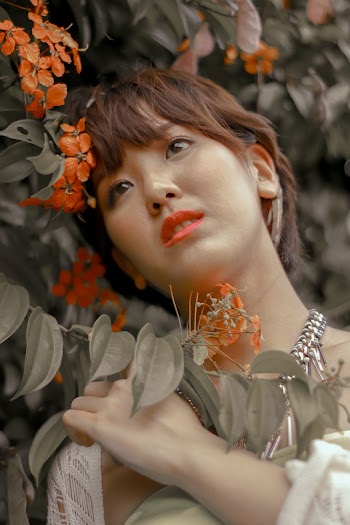 Woman Wearing A Necklace Besides Orange Flowers