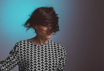 Woman wearing a patterned sweater flips her short hair in front of her face