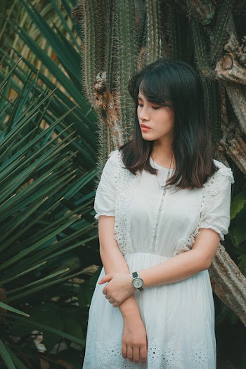 Woman Wearing a Teal Half-sleeved Dress standing Beside Green Plant
