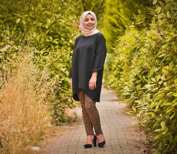 Woman wearing a white headscarf standing on a footpath