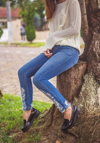 Woman wearing a white sweater top sitting on a log