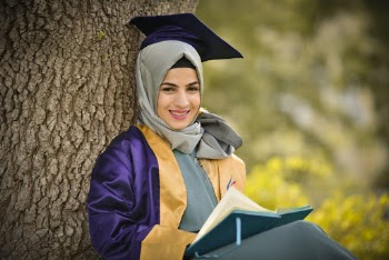 Woman Wearing Academic Dress Leaning on Tree