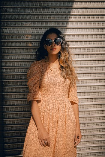 Woman Wearing an Orange Dress and Heart shaped Glasses Leaning on Wall