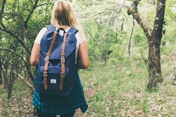 woman wearing backpack walking on forest